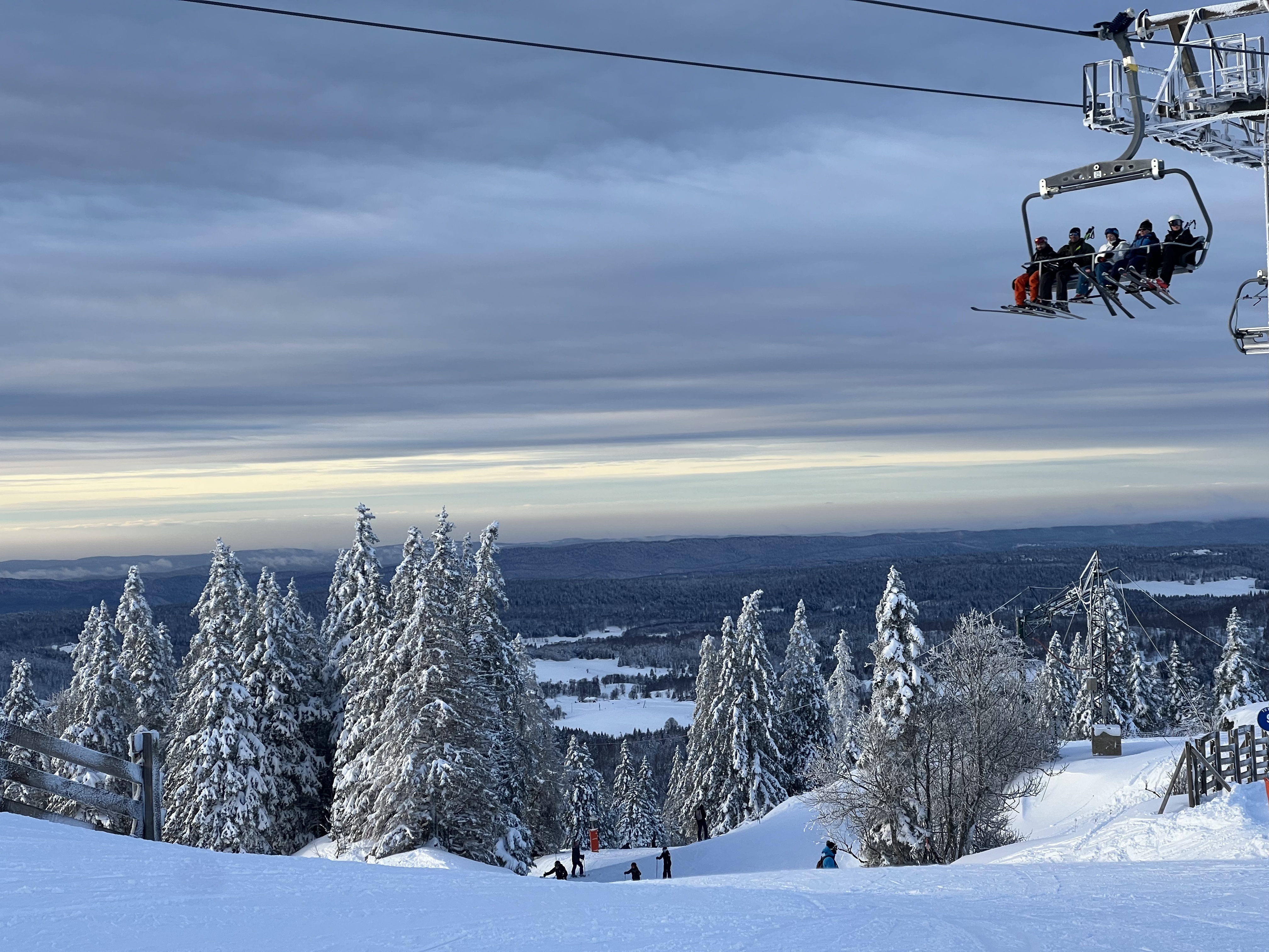 Looking west from the ski area — snow-covered Jura forest and the plateau below